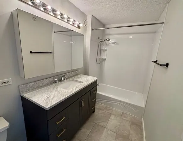 a bathroom with a granite countertop sink mirror and a bathtub