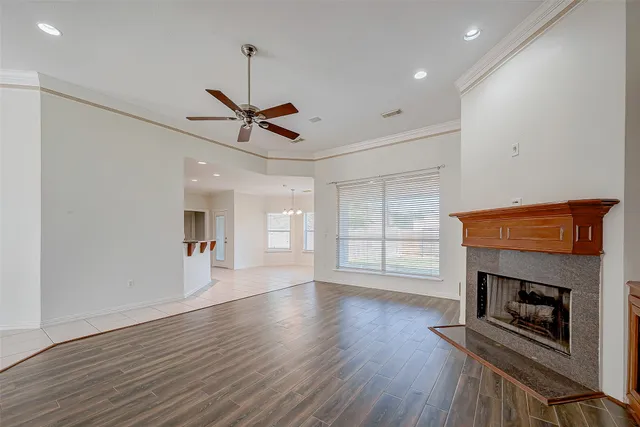 wooden floor in an empty room with a fireplace and a window
