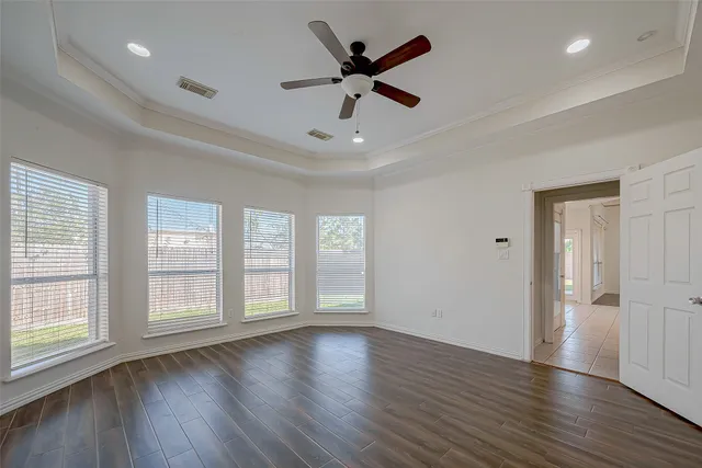 an empty room with wooden floor ceiling fan and window