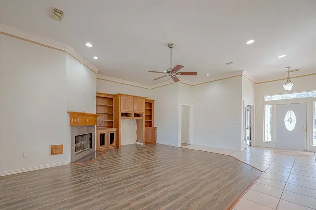 an empty room with wooden floor and a ceiling fan