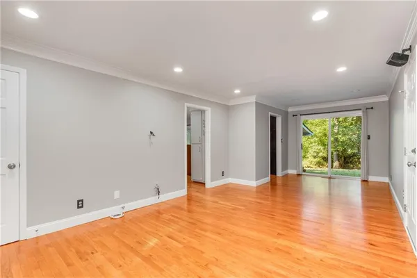a view of an empty room with wooden floor and a window