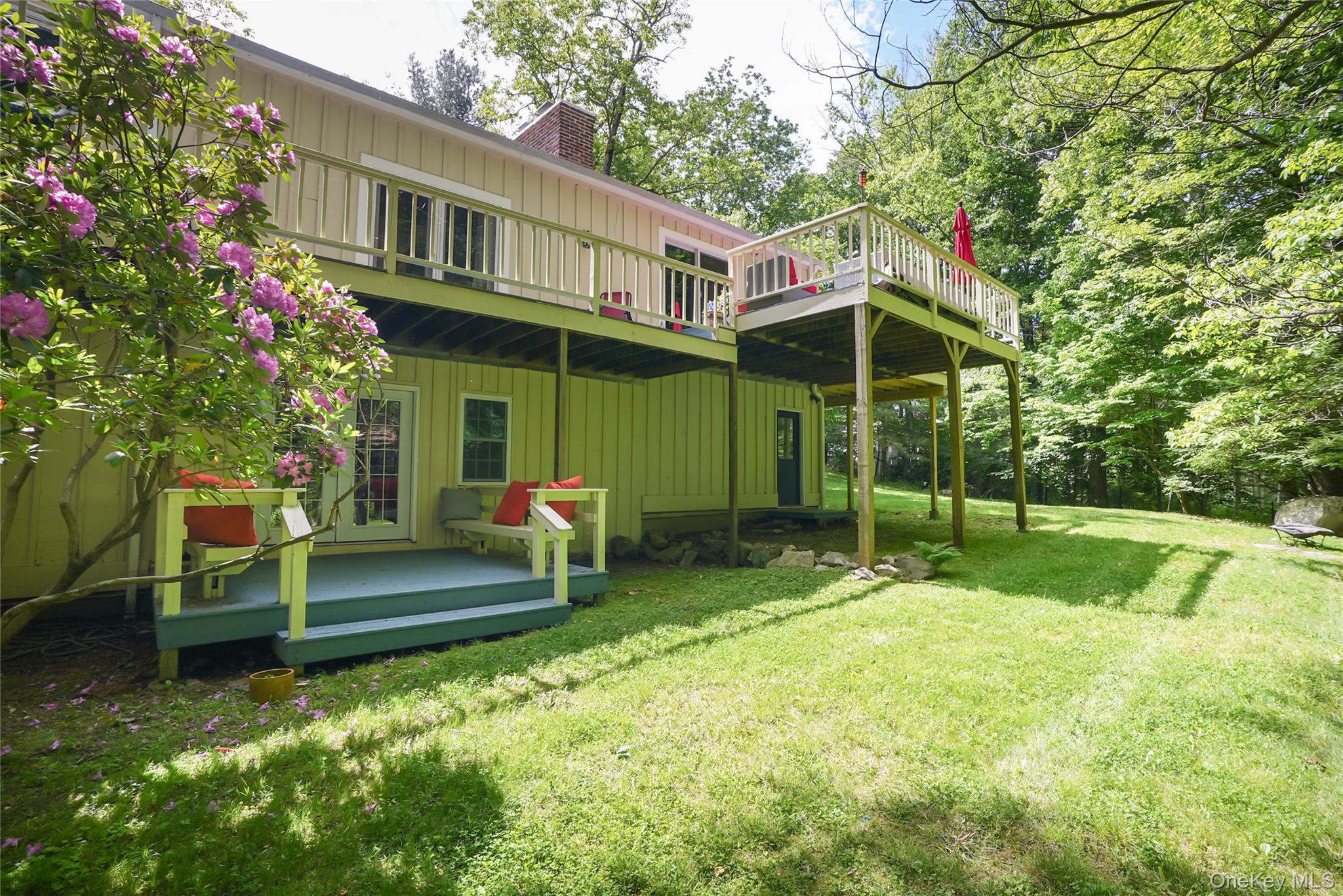 22 Peters Lane Pound Ridge, NY 10576 - Photo 42 of 43 Expansive rear yard featuring a large elevated wood deck with railing, a ground-level wood deck, a brick chimney, and mature trees