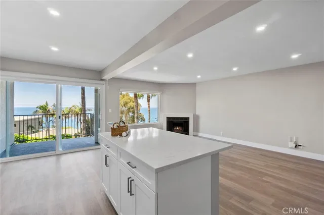 a large white kitchen with wooden floor and natural light