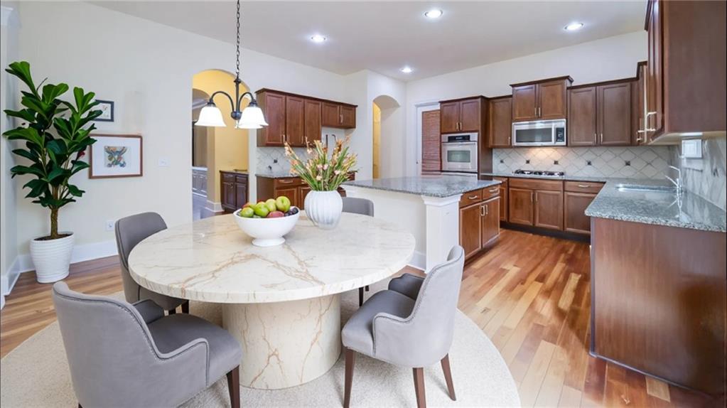 2220 Stirling Bridge Road Cumming, GA 30041 - Photo 22 of 82 a kitchen with stainless steel appliances kitchen island granite countertop a refrigerator a stove a sink a dining table and chairs with wooden floor