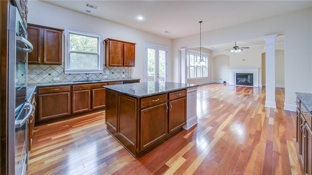2220 Stirling Bridge Road Cumming, GA 30041 - Photo 24 of 82 a kitchen with stainless steel appliances granite countertop hardwood floor sink stove dining table and chairs