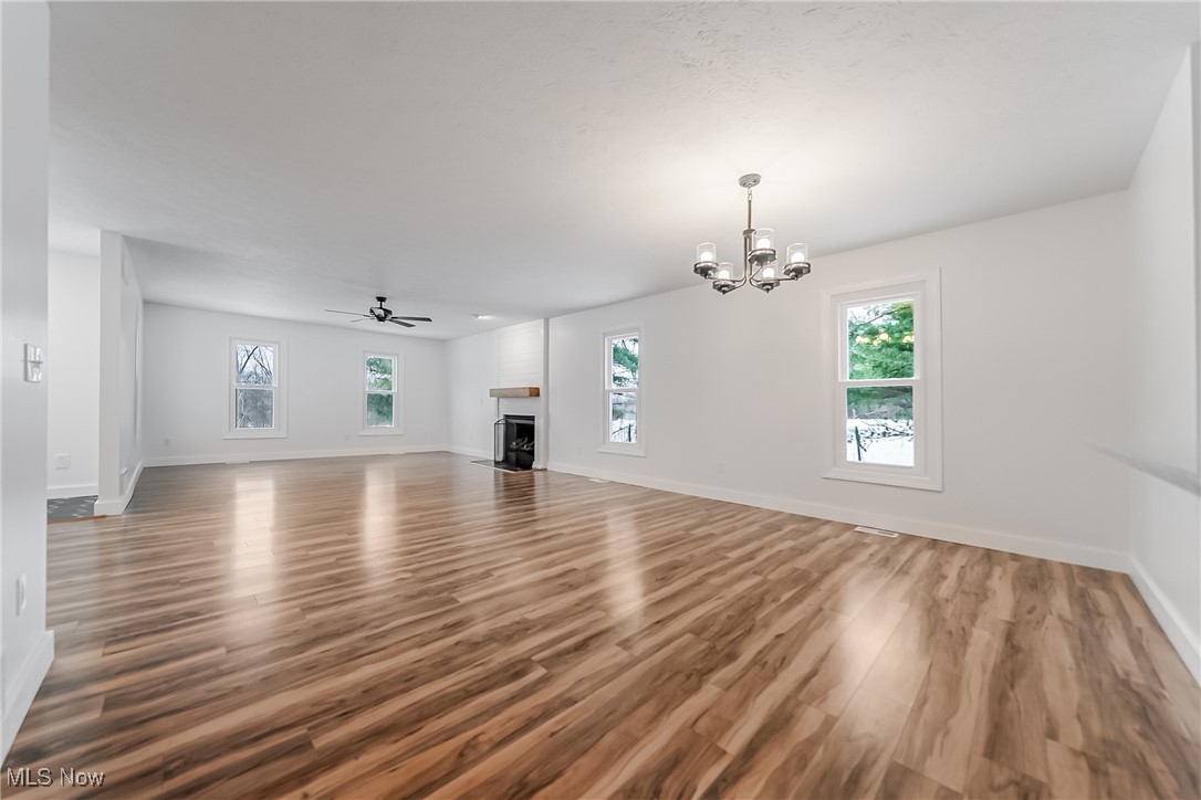7488 Greenwich Road Seville, OH 44273 - Photo 8 of 37 Unfurnished living room featuring a ceiling fan, a fireplace, light wood finished floors, and a chandelier