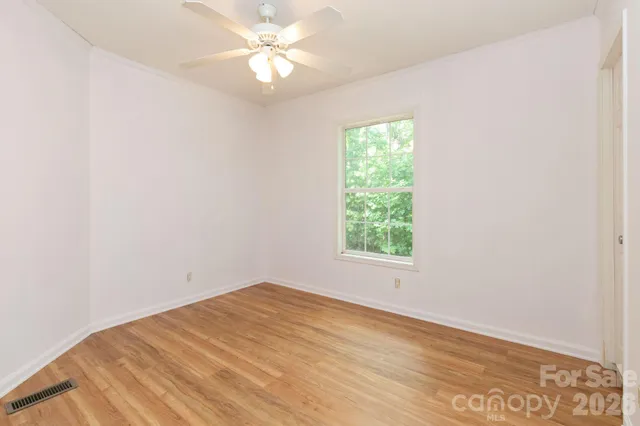 an empty room with a window and a fan