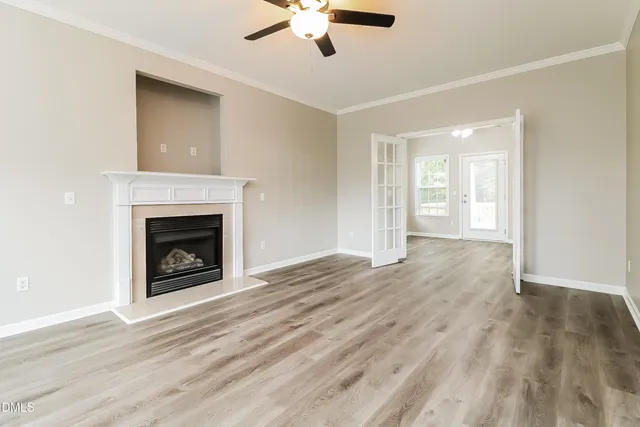 a view of an empty room with wooden floor fireplace and a window
