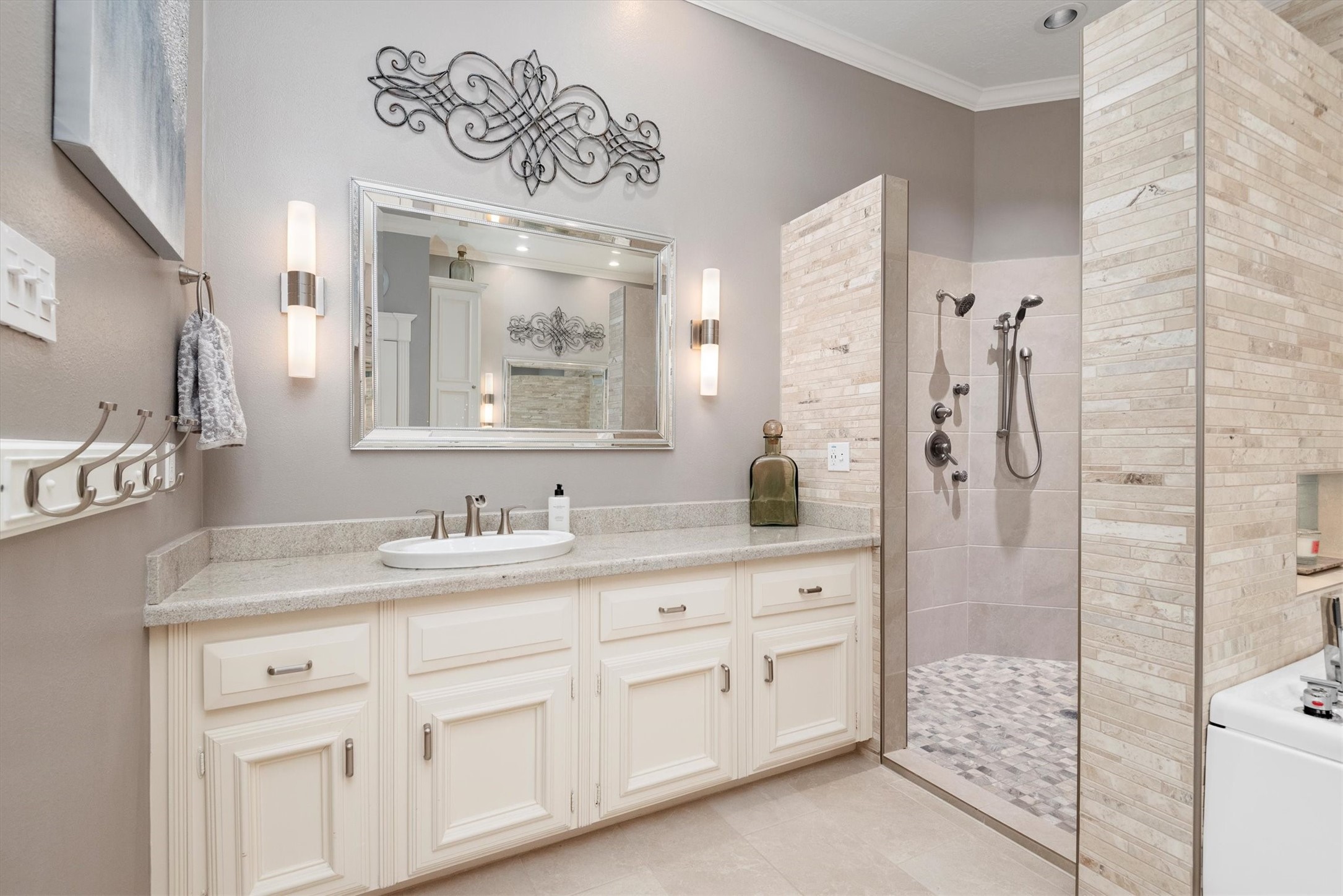 16022 Stewarts Grove Drive Spring, TX 77379 - Photo 26 of 45 PRIMARY BATHROOM: Another view of the primary bathroom showcases custom tile work, travertine accents, granite countertops, custom wood cabinetry, a soft gray paint color, neutral floor tiles, and a custom roman shade.