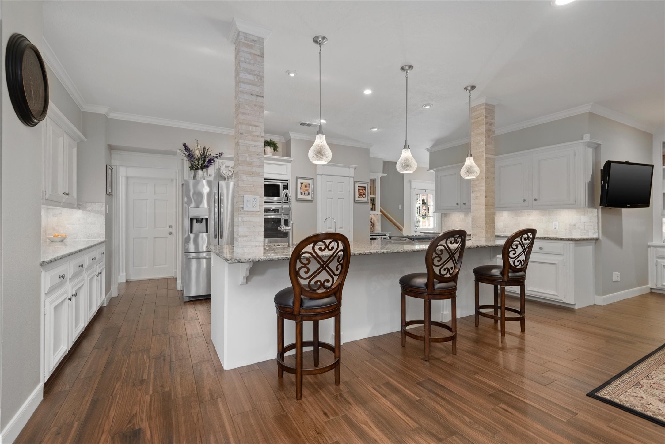 16022 Stewarts Grove Drive Spring, TX 77379 - Photo 2 of 45 KITCHEN: 22’ X 15’ with a 9’ ceiling height. WALK-IN PANTRY: 6’ X 5’ with 9’ ceiling height. A spacious granite countertop extends to provide ample counter seating, for engaging in conversation or preparing meals for a busy family. Includes neutral beige paint color, crown molding, custom wood cabinetry, 3 expansive granite countertops, travertine accents, high ceilings, LED lighting, stainless steel appliances, gas stove & wood-like porcelain tile flooring.