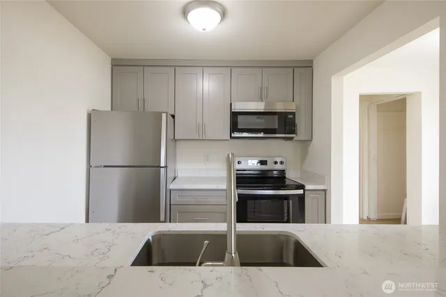 a kitchen that has a refrigerator a stove and white cabinets