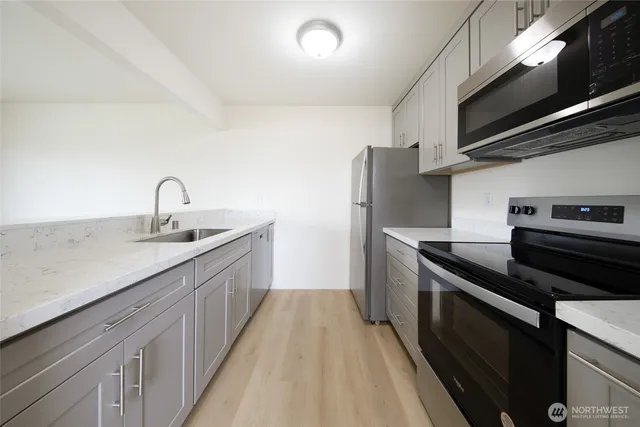 a kitchen with stainless steel appliances granite countertop a sink a stove and a refrigerator