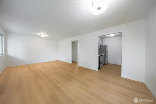 a view of an empty room with wooden floor and a window
