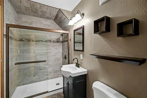 a bathroom with a sink a toilet and shower