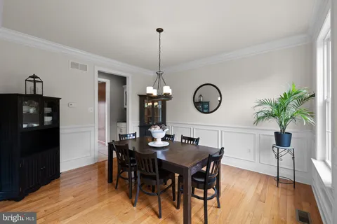 a dining room with wooden floor a chandelier a wooden table and chairs