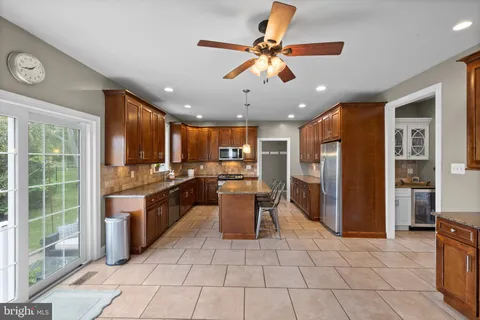 a kitchen with stainless steel appliances granite countertop a refrigerator a sink a stove top oven and a dining table
