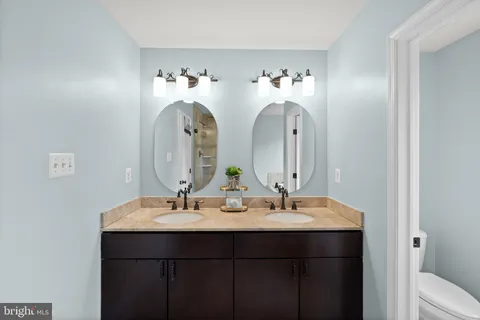 a bathroom with a double vanity sink a mirror and a toilet