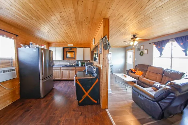 a living room with stainless steel appliances kitchen island granite countertop a table chairs and a refrigerator