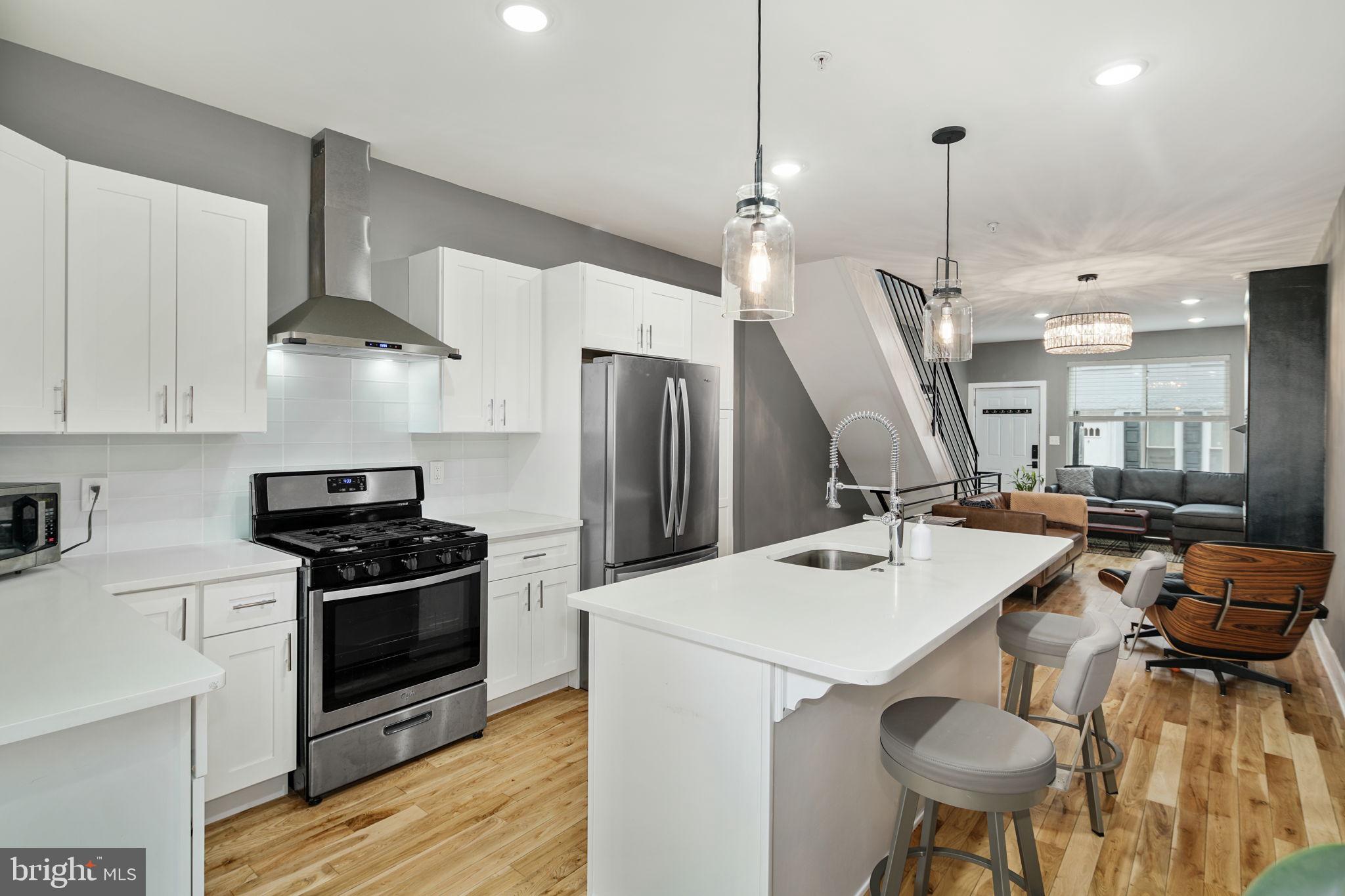 a kitchen with stainless steel appliances a stove a sink a island and chairs