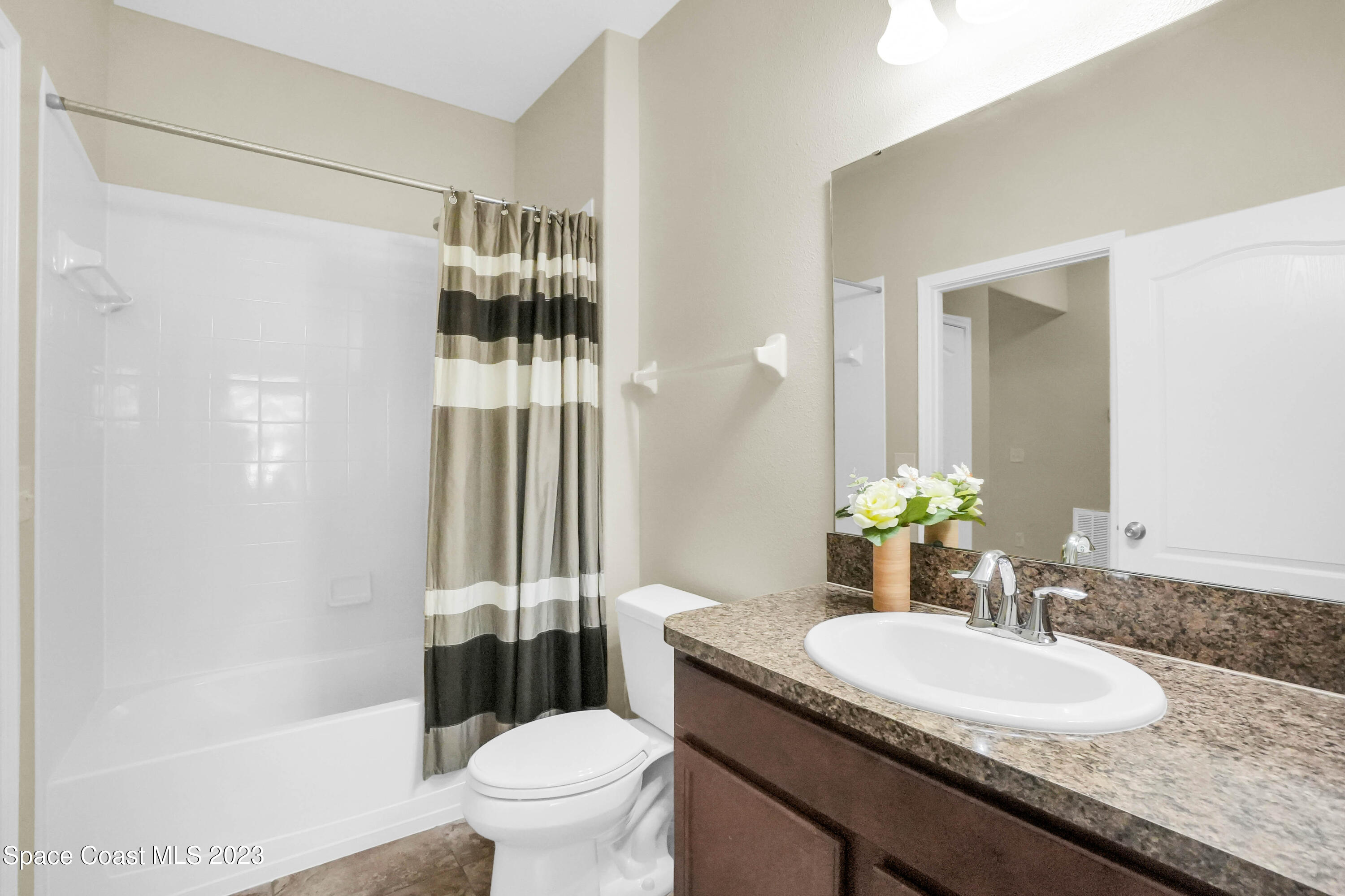 5928 Van Ness Drive Melbourne, FL 32940 - Photo 17 of 35 a bathroom with a granite countertop sink toilet a mirror and shower