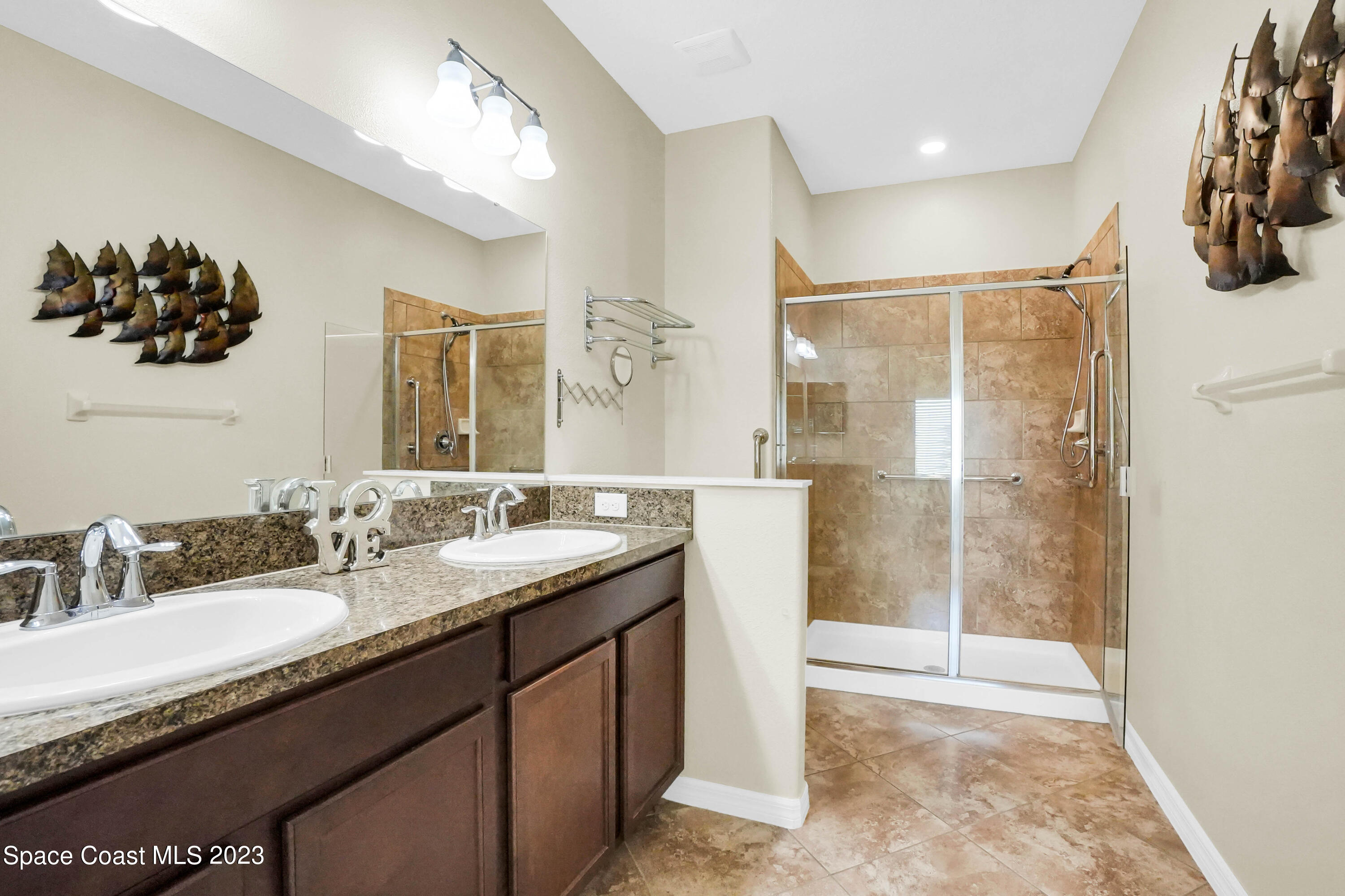 5928 Van Ness Drive Melbourne, FL 32940 - Photo 19 of 35 a bathroom with a granite countertop sink a mirror and a shower