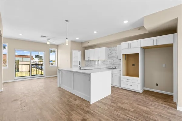 a large white kitchen with kitchen island a large counter space a sink stainless steel appliances and cabinets