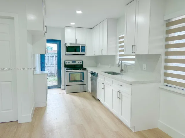 a large kitchen with stainless steel appliances granite countertop a lot of counter space and wooden floors