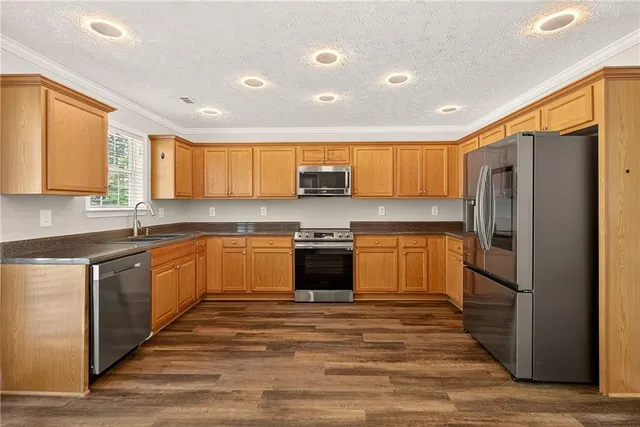 a kitchen with stainless steel appliances granite countertop a refrigerator and wooden cabinets