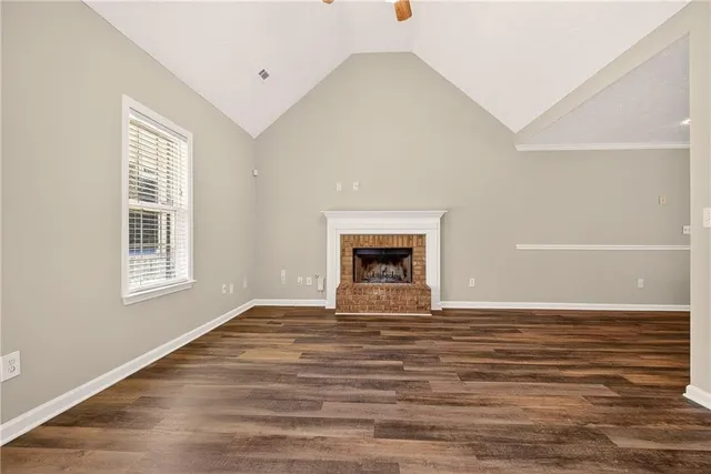a view of an empty room with window and wooden floor
