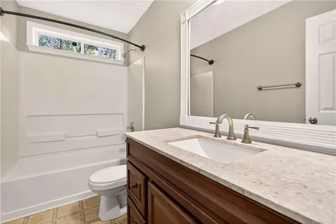 a bathroom with a granite countertop toilet sink and mirror