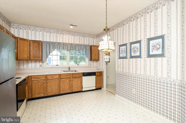 a large white kitchen with a sink a window and stainless steel appliances
