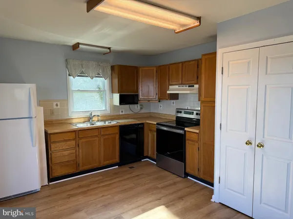 a kitchen with granite countertop a refrigerator stove top oven and sink