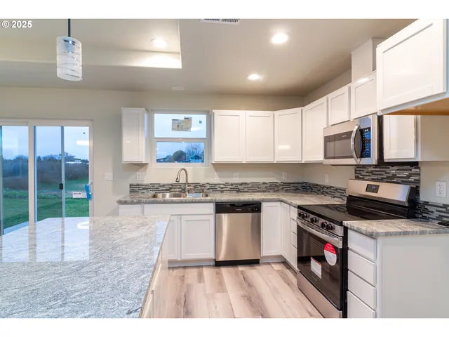 a kitchen with stainless steel appliances granite countertop a stove a sink and a microwave