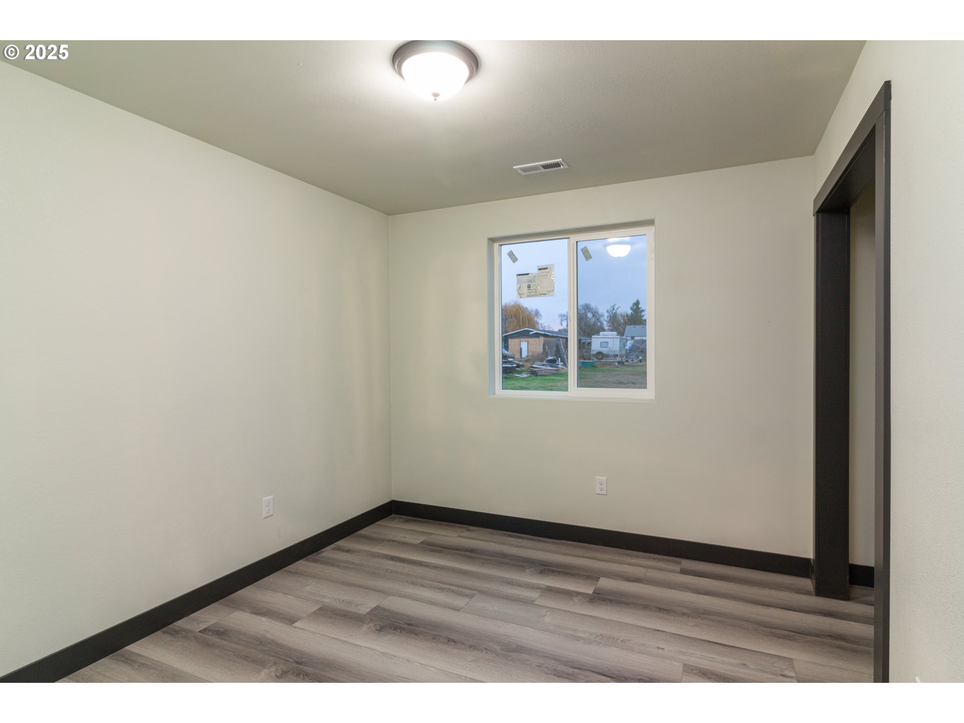 435 Northeast Sloan Street Stanfield, OR 97875 - Photo 9 of 24 an empty room with wooden floor and windows