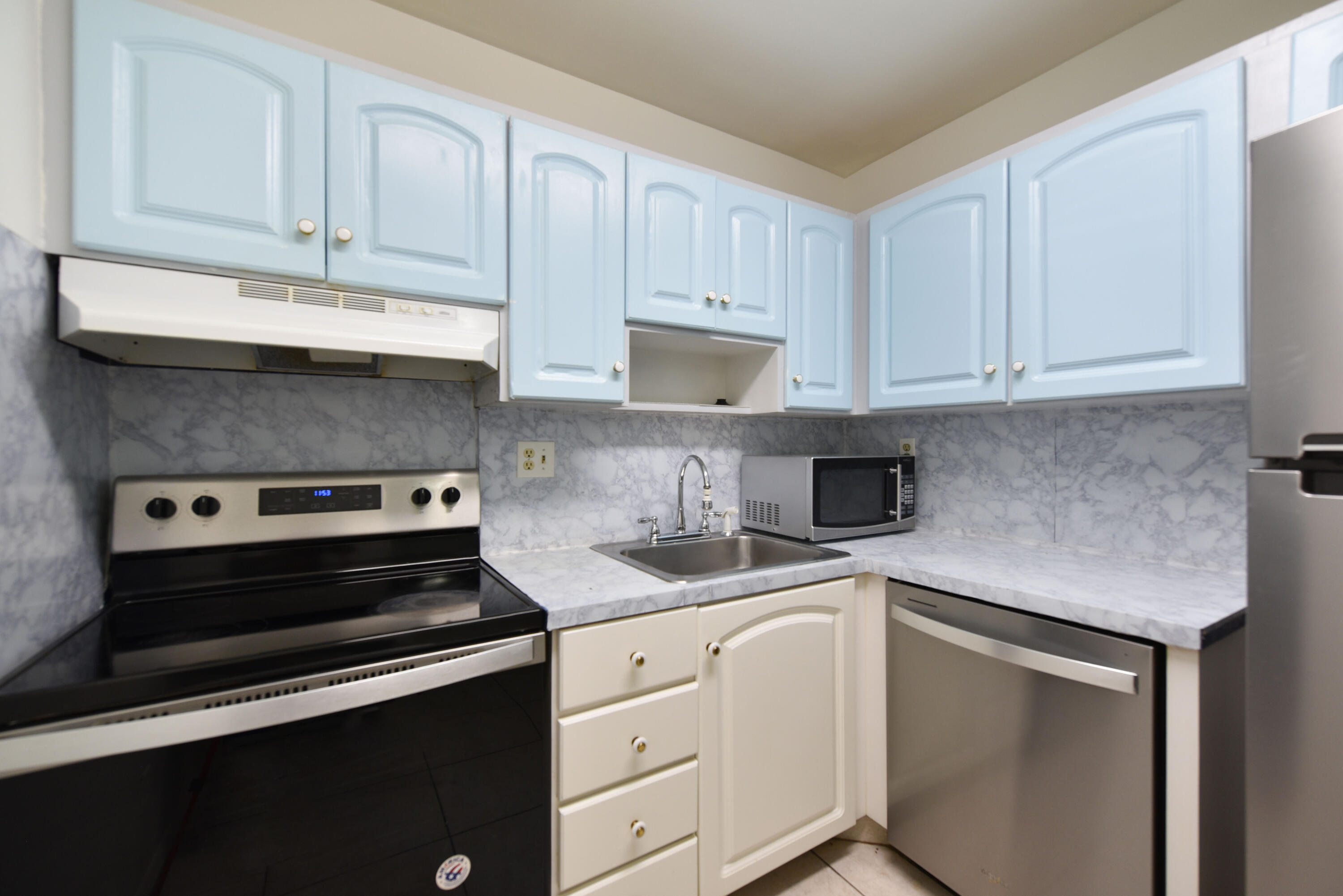 298 Southwest 6th Street, Unit 110 Boca Raton, FL 33432 - Photo 11 of 27 a kitchen with granite countertop a sink stove and cabinets