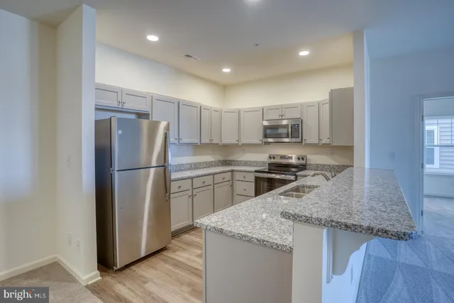 a kitchen with stainless steel appliances granite countertop a refrigerator a stove a sink and a microwave