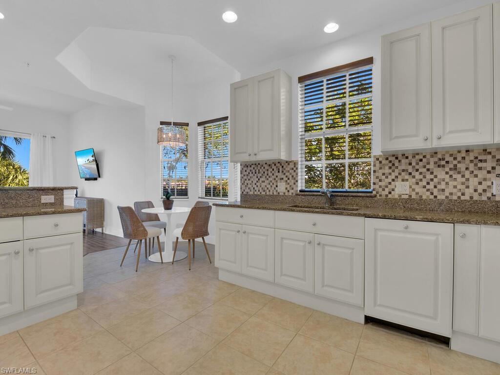 2710 Callista Court, Unit 104 Naples, FL 34114 - Photo 13 of 43 a kitchen with granite countertop white cabinets and white appliances