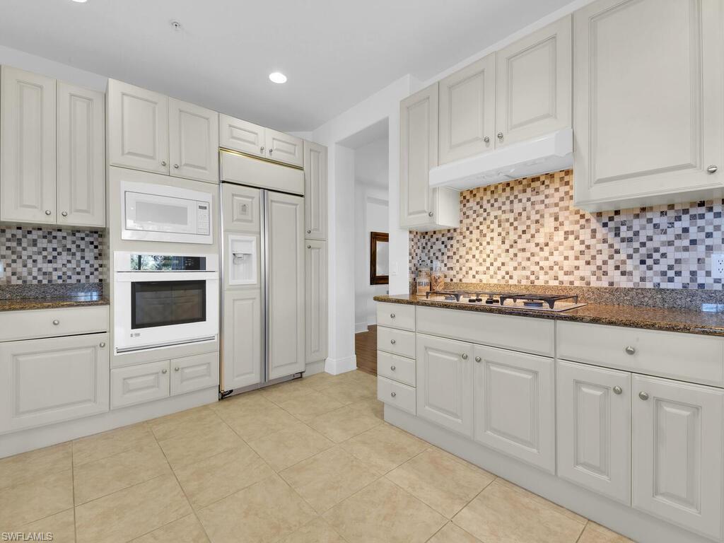 2710 Callista Court, Unit 104 Naples, FL 34114 - Photo 14 of 43 a kitchen with white cabinets and white appliances