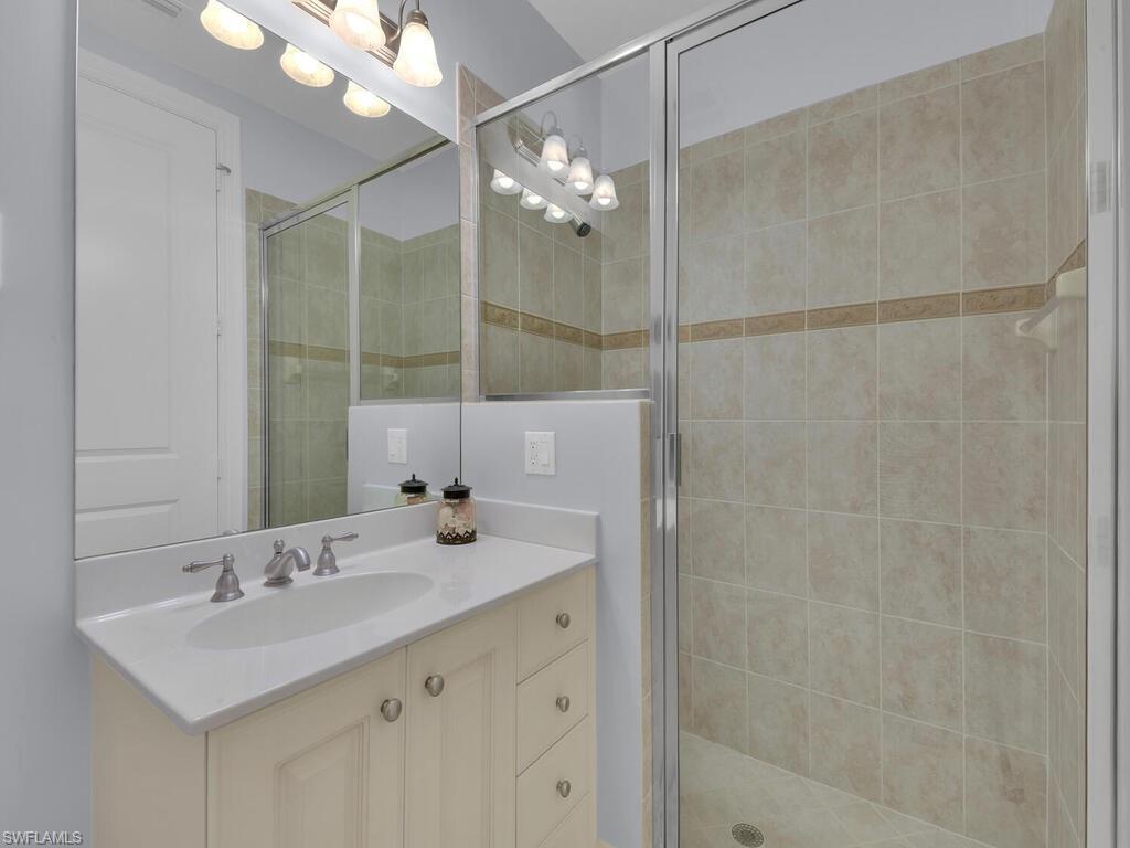 2710 Callista Court, Unit 104 Naples, FL 34114 - Photo 24 of 43 a bathroom with a sink a large mirror and a shower