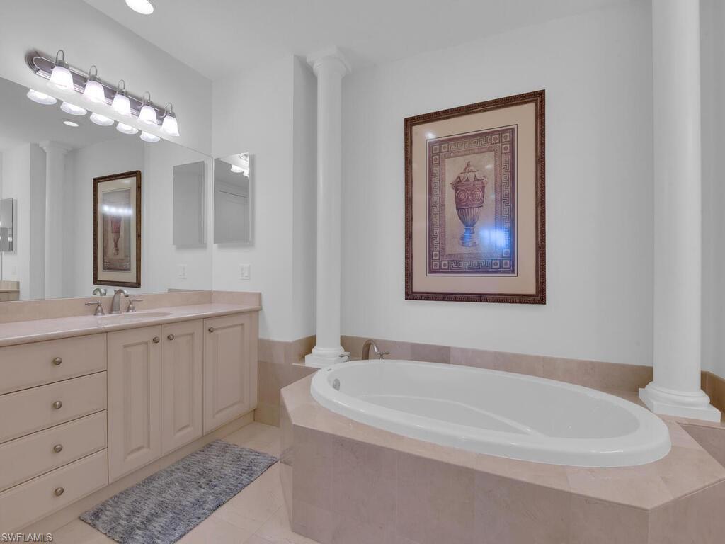 2710 Callista Court, Unit 104 Naples, FL 34114 - Photo 27 of 43 a bathroom with a bathtub a double vanity sink and a mirror