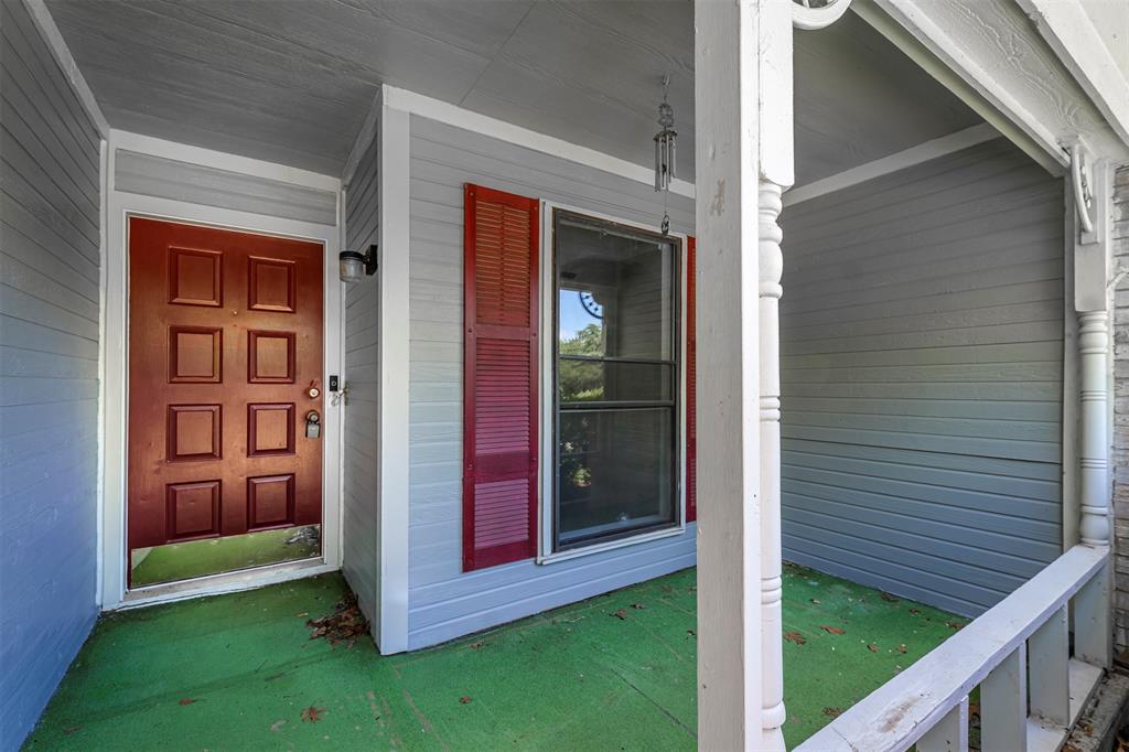 617 Rolling Ridge Court Azle, TX 76020 - Photo 2 of 20 Covered front porch featuring gray siding, a red paneled entry door, a window with red louvered shutters, and white architectural columns