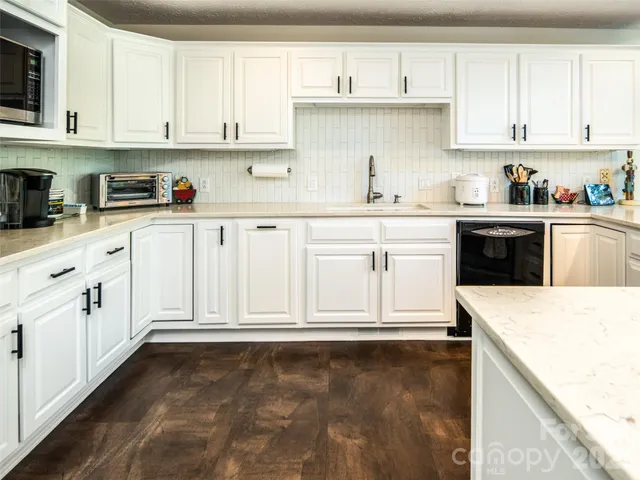 a kitchen with granite countertop white cabinets and white appliances
