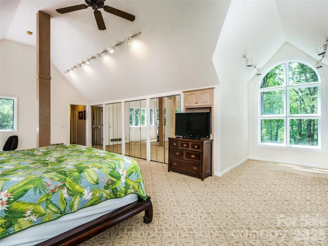 a bed room with a bed television and a large window