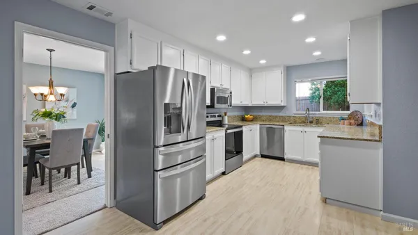 a kitchen with white cabinets and stainless steel appliances