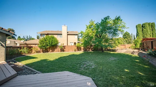 a backyard of a house with table and chairs potted plants and large tree