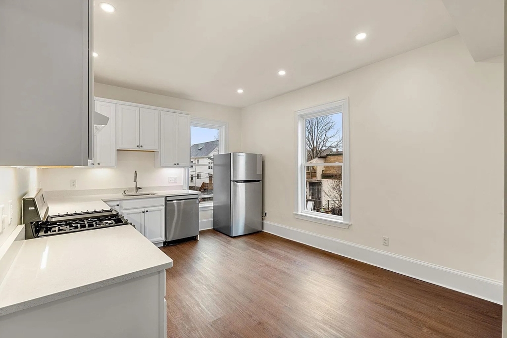 10 King Street, Unit 2 Boston, MA 02122 - Photo 4 of 17 a kitchen with granite countertop a stove a sink dishwasher and a refrigerator with wooden floor