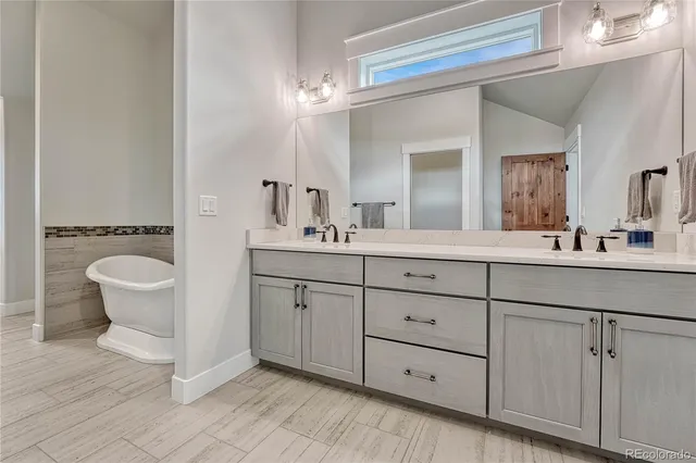 a bathroom with a double vanity sink a mirror and a bathtub