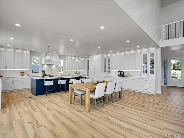 a kitchen with stainless steel appliances kitchen island granite countertop a table chairs sink refrigerator and cabinets