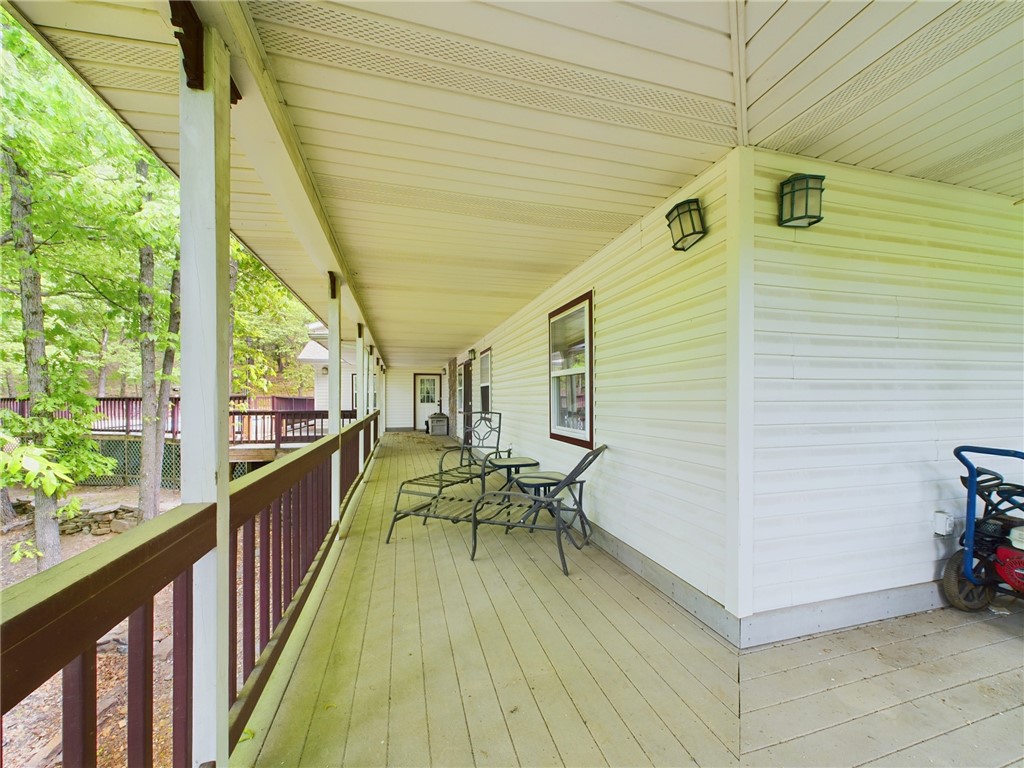 12883 Nickels Road West Fork, AR 72774 - Photo 18 of 26 Expansive covered porch featuring wood-finish flooring, wood railings, white vinyl siding, and recessed outdoor lighting