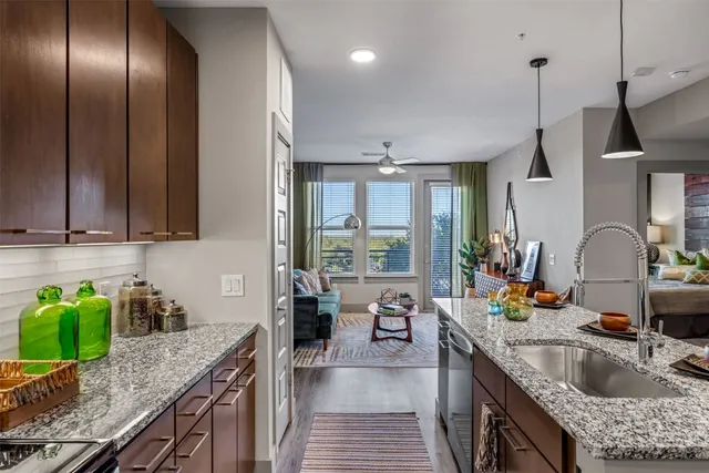 a kitchen with stainless steel appliances granite countertop a sink a stove and a wooden floors